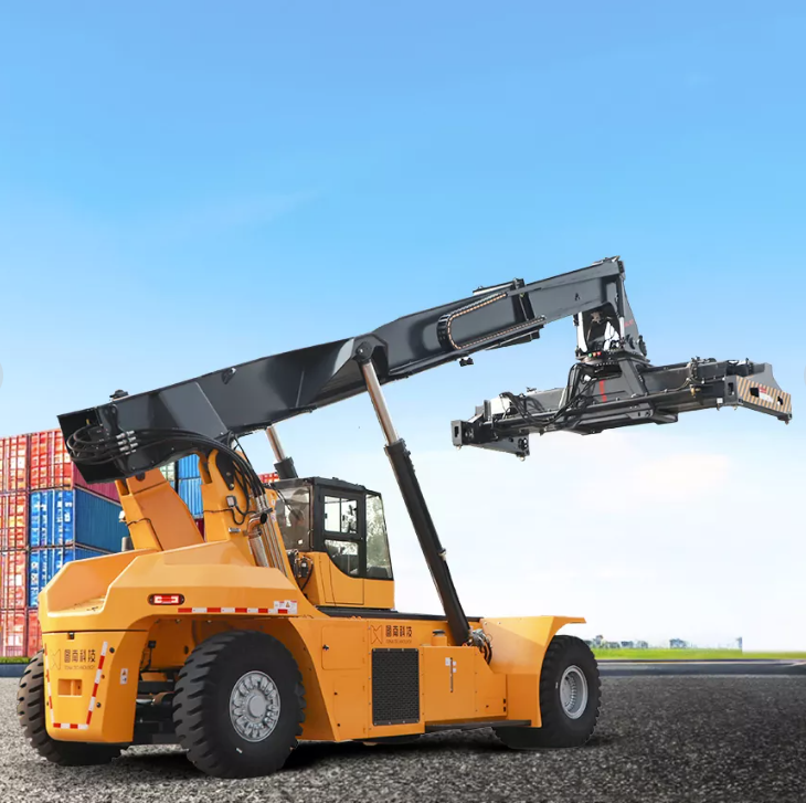 A reach stacker lifting a large shipping container in a busy port terminal.